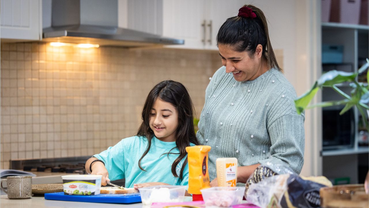 Mother and daughter preparing food in family home kitchen