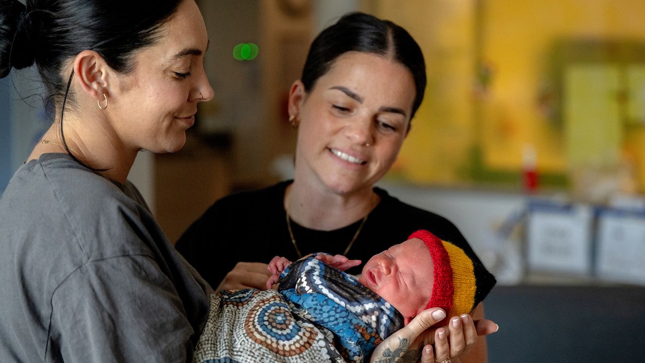 Two women holding a newborn baby
